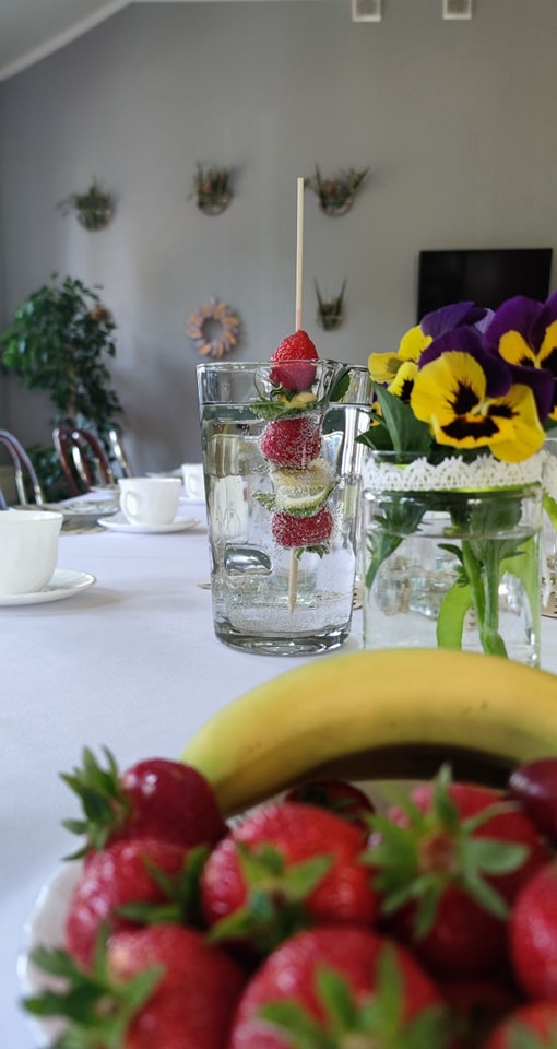 Fotografia owoców oraz szklanki wody z owocami stojących na stole.