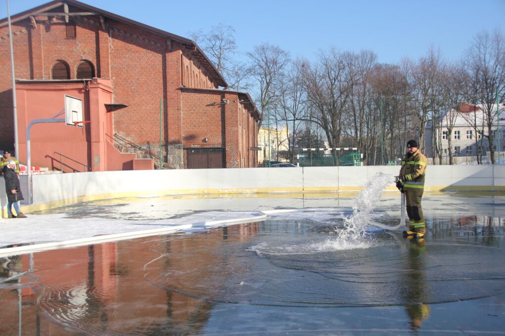 Przedstawia strażaka uzupełniającego wodę 
